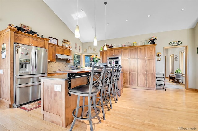 96 Garnet Ln, Pine, CO 80470 - kitchen with stainless steel appliances, light wood-style flooring, under cabinet range hood, a breakfast bar, and high vaulted ceiling