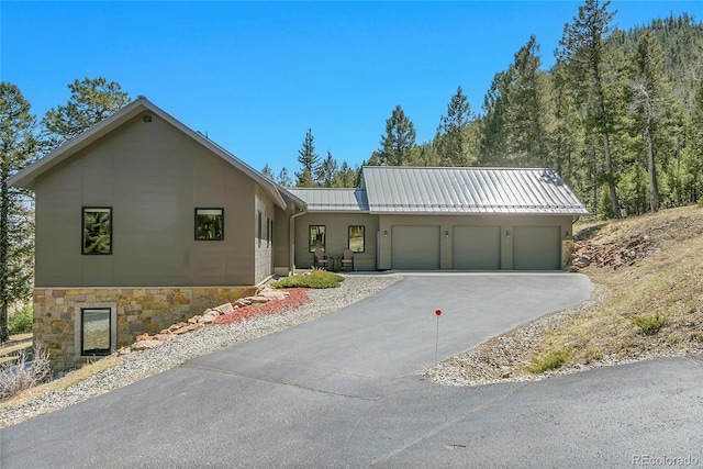96 Garnet Ln, Pine, CO 80470 - view of front of home with a garage, driveway, a metal roof, a standing seam roof, and stone siding