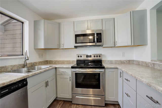 kitchen featuring dark wood finished floors, light countertops, appliances with stainless steel finishes, and a sink