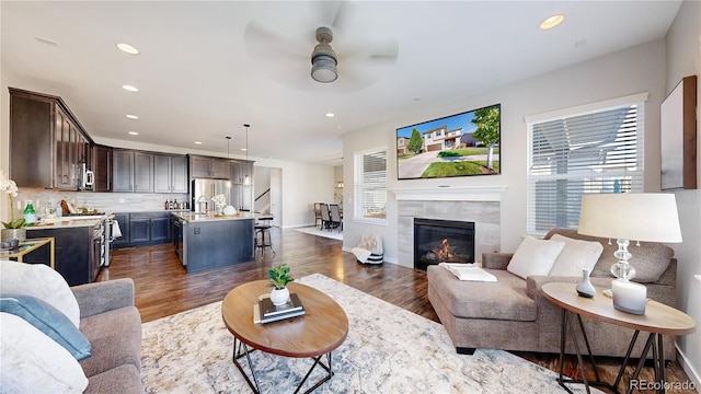 living room with ceiling fan, a wealth of natural light, a fireplace, and dark hardwood / wood-style flooring