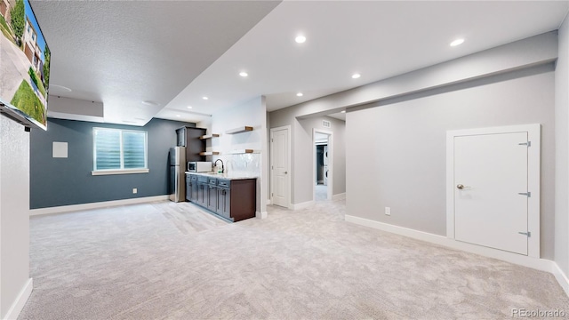 kitchen featuring appliances with stainless steel finishes, light colored carpet, sink, and a textured ceiling