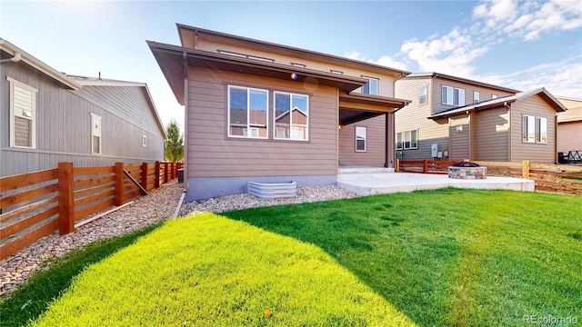 back of property with a lawn, a patio, and a fire pit