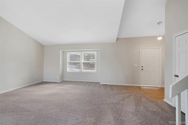 empty room with carpet floors, lofted ceiling, and baseboards