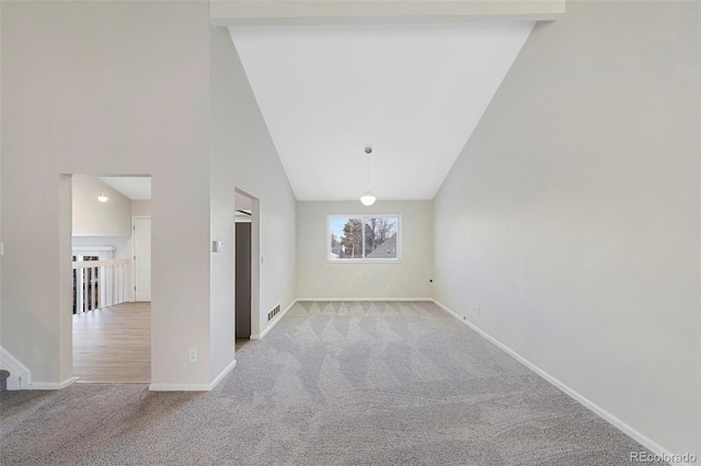 empty room featuring high vaulted ceiling, light carpet, visible vents, and baseboards