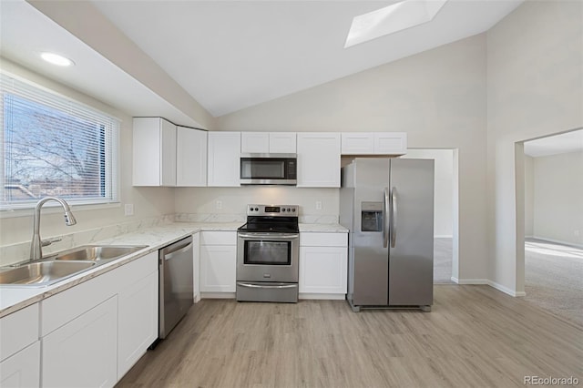 kitchen featuring a skylight, stainless steel appliances, light wood-style flooring, white cabinets, and a sink