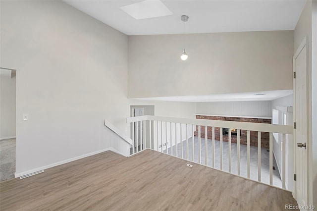 unfurnished room featuring a skylight, baseboards, visible vents, and wood finished floors