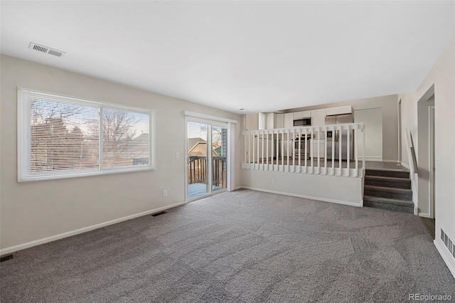 carpeted spare room featuring visible vents, baseboards, and stairs