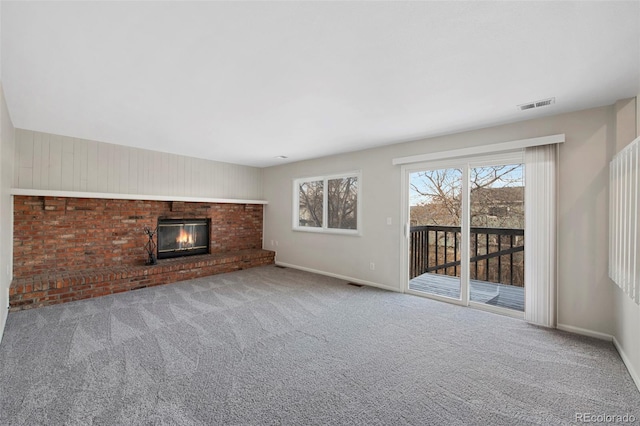 unfurnished living room with a fireplace, carpet flooring, visible vents, and baseboards