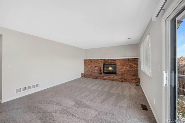 unfurnished living room featuring a brick fireplace, visible vents, baseboards, and carpet flooring