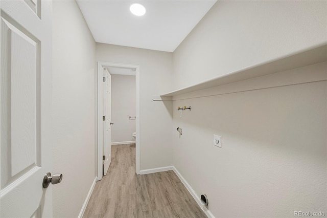 clothes washing area featuring light wood-style floors, laundry area, and baseboards