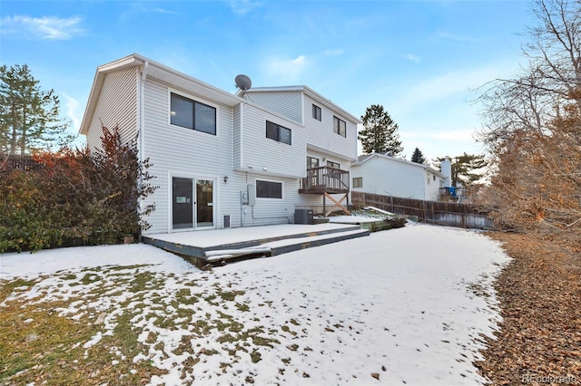 snow covered rear of property with fence and a wooden deck