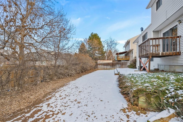 yard covered in snow featuring a wooden deck and fence