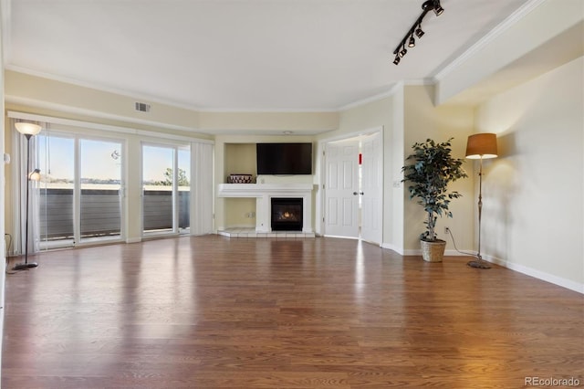 unfurnished living room featuring rail lighting, hardwood / wood-style flooring, and ornamental molding