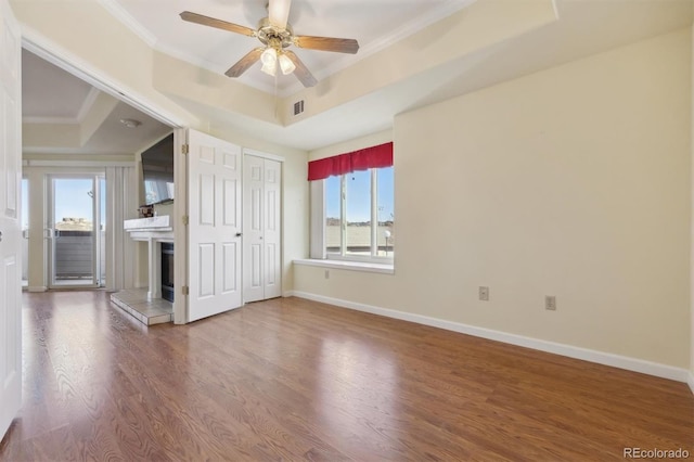 unfurnished room featuring hardwood / wood-style floors, ceiling fan, crown molding, and a tray ceiling