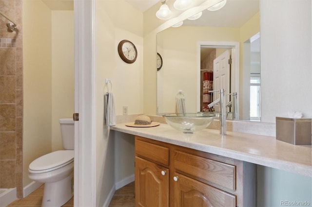 bathroom with a tile shower, vanity, and toilet