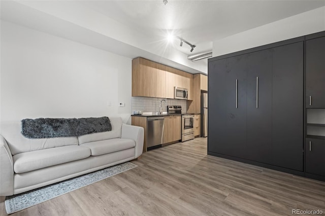 living room with rail lighting, sink, and light hardwood / wood-style flooring