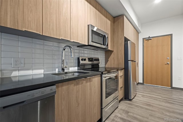 kitchen with sink, a barn door, light brown cabinetry, tasteful backsplash, and stainless steel appliances