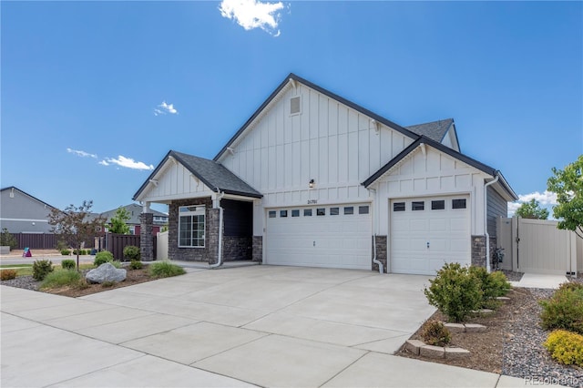 21701 E 50th Dr, Aurora, CO 80019 - view of front facade featuring board and batten siding, an attached garage, driveway, stone siding, and a gate