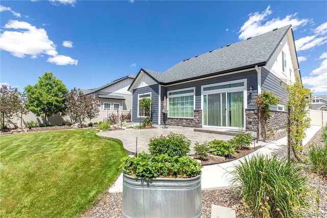 21701 E 50th Dr, Aurora, CO 80019 - back of house featuring a patio area, stone siding, board and batten siding, and roof with shingles