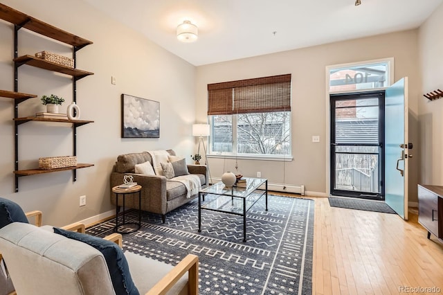 living area with wood-type flooring, a baseboard radiator, and baseboards