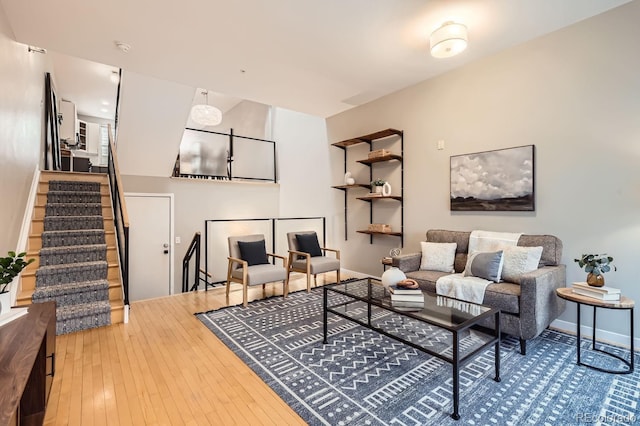 living room with stairway, wood-type flooring, and baseboards