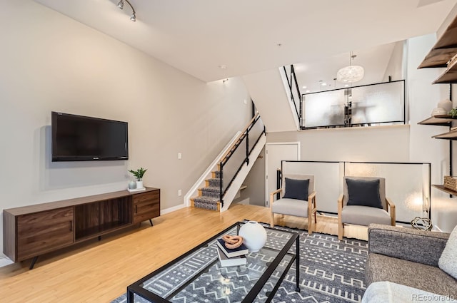 living room with stairs, baseboards, and wood finished floors