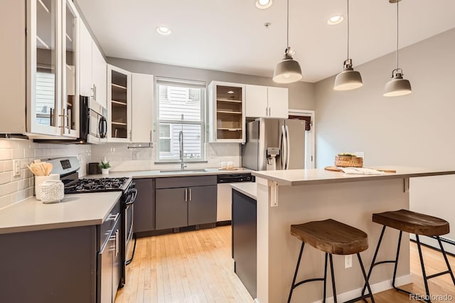 kitchen featuring a sink, stainless steel appliances, light countertops, a kitchen bar, and backsplash