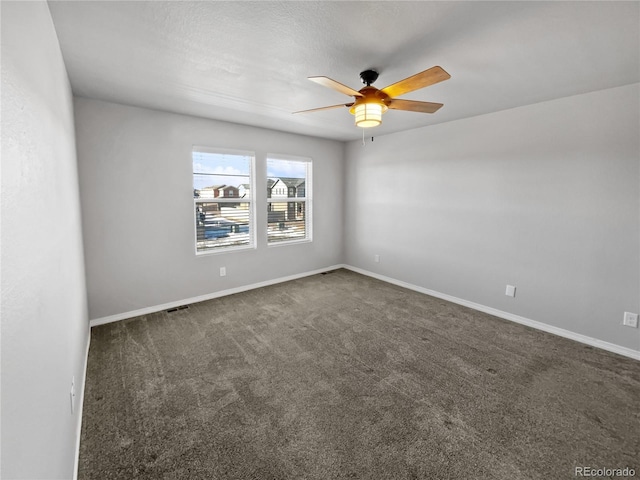 spare room with ceiling fan and dark carpet