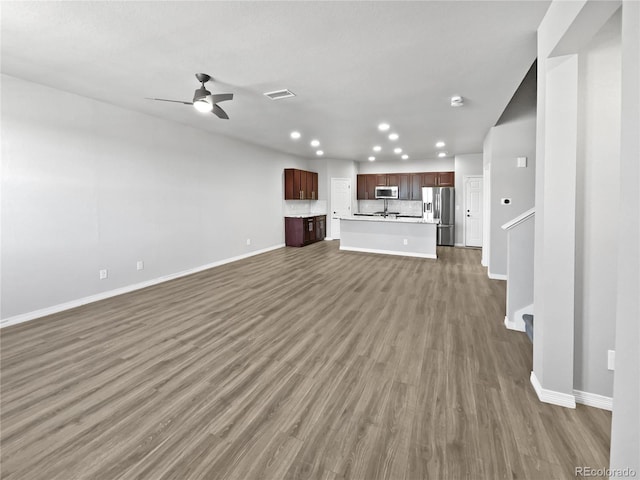 unfurnished living room featuring dark wood-type flooring and ceiling fan