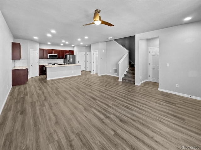 unfurnished living room featuring ceiling fan and dark hardwood / wood-style flooring