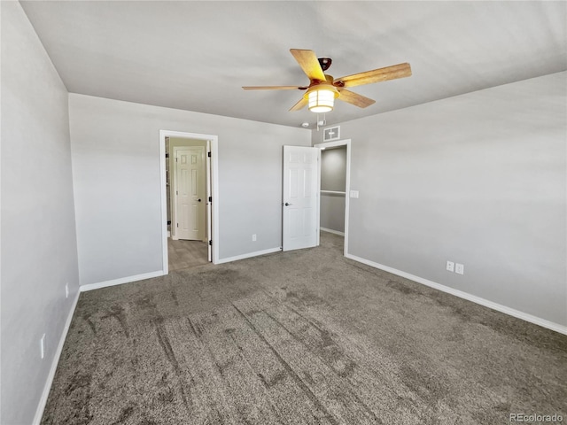 unfurnished bedroom featuring a walk in closet, carpet floors, and ceiling fan