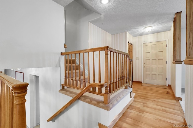 11936 E Oregon Cir, Aurora, CO 80012 - stairs with a textured ceiling, wood finished floors, and baseboards