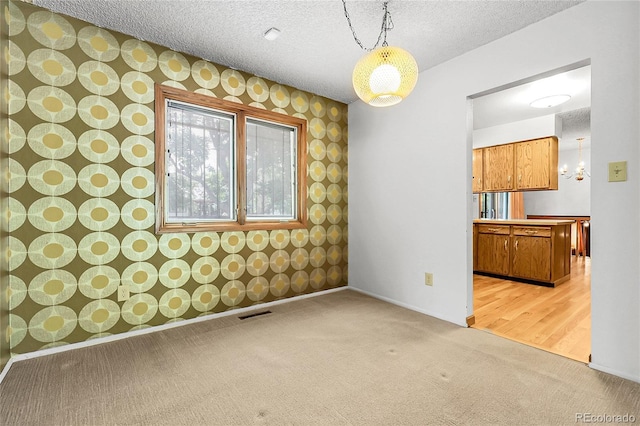 11936 E Oregon Cir, Aurora, CO 80012 - carpeted spare room with wallpapered walls, a chandelier, baseboards, and a textured ceiling