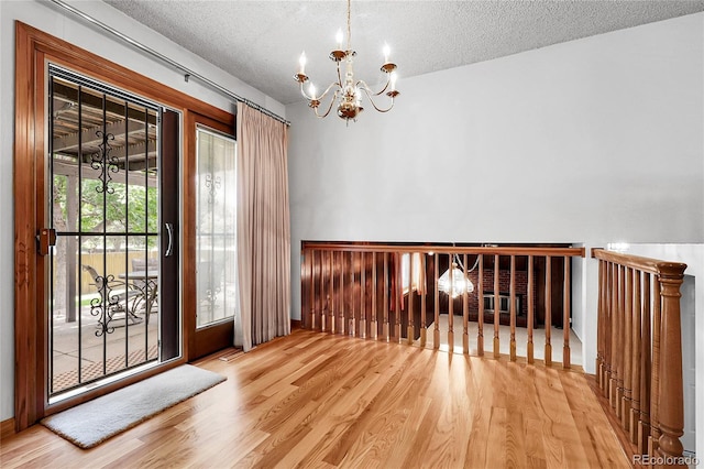 11936 E Oregon Cir, Aurora, CO 80012 - spare room with a chandelier, wood finished floors, and a textured ceiling