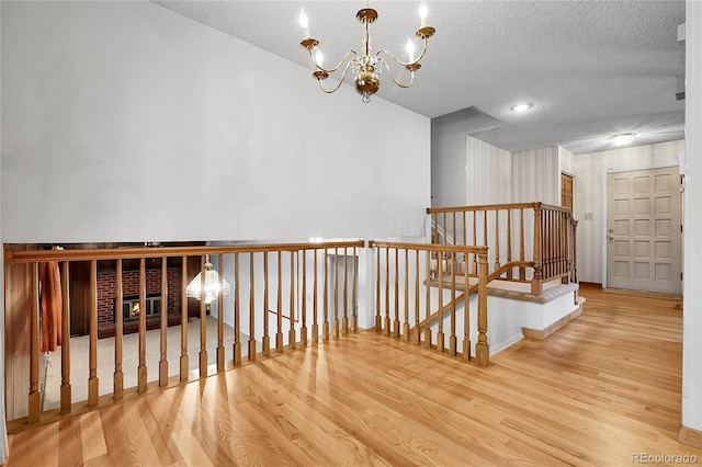 11936 E Oregon Cir, Aurora, CO 80012 - hall featuring wood finished floors, a textured ceiling, a chandelier, an upstairs landing, and baseboards
