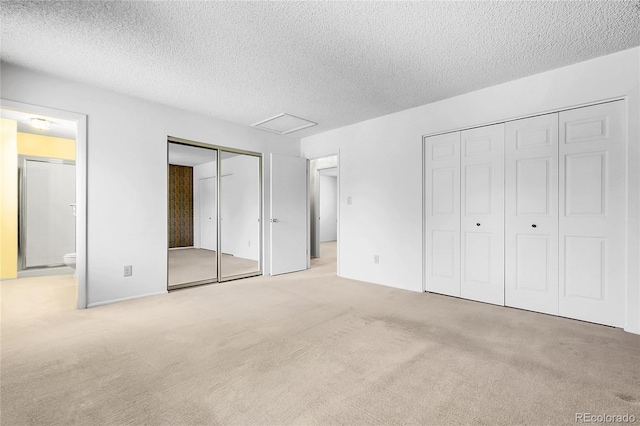11936 E Oregon Cir, Aurora, CO 80012 - unfurnished bedroom featuring two closets, carpet flooring, a textured ceiling, ensuite bath, and attic access