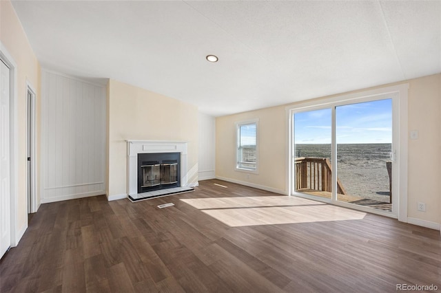 63560 Huckleberry Rd, Fowler, CO 81039 - unfurnished living room featuring dark wood finished floors, baseboards, a glass covered fireplace, and recessed lighting
