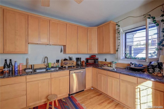 kitchen featuring dishwasher, light wood-type flooring, dark stone countertops, and sink