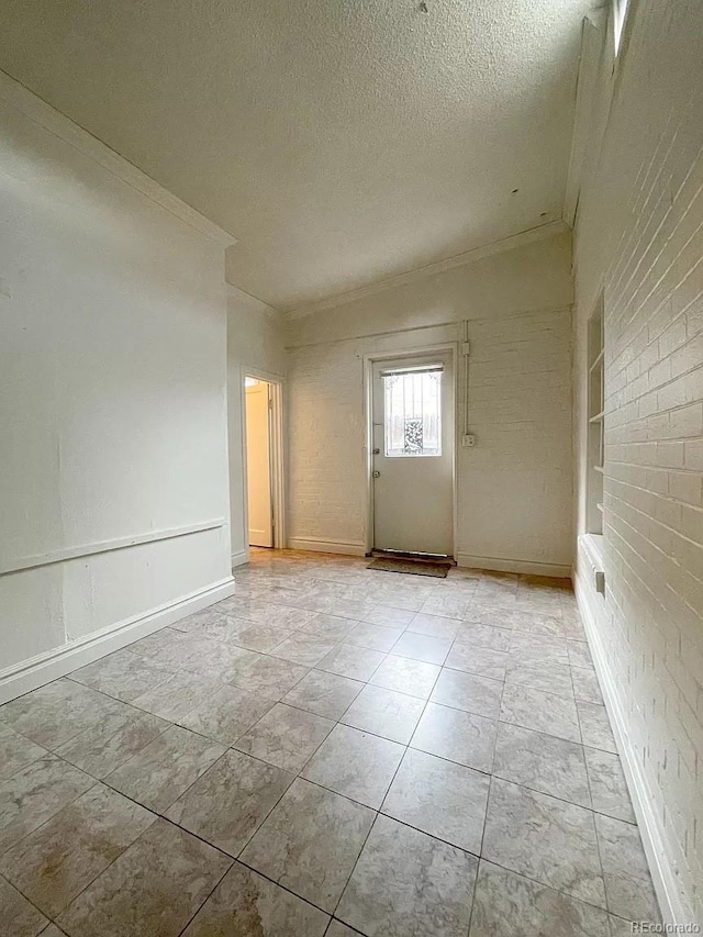 spare room featuring ornamental molding, a textured ceiling, and brick wall