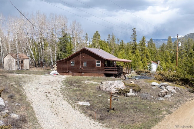 479 County Road 465, Grand Lake, CO 80447 - view of home's exterior featuring log siding, dirt driveway, a wooded view, and metal roof