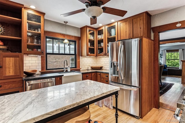 3145 W 31st Ave, Denver, CO 80211 - kitchen featuring appliances with stainless steel finishes, brown cabinets, light wood-style flooring, light stone counters, and recessed lighting