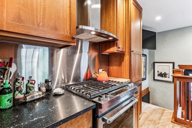 3145 W 31st Ave, Denver, CO 80211 - kitchen featuring wall chimney range hood, stainless steel range with gas stovetop, brown cabinets, tasteful backsplash, and light wood-style flooring