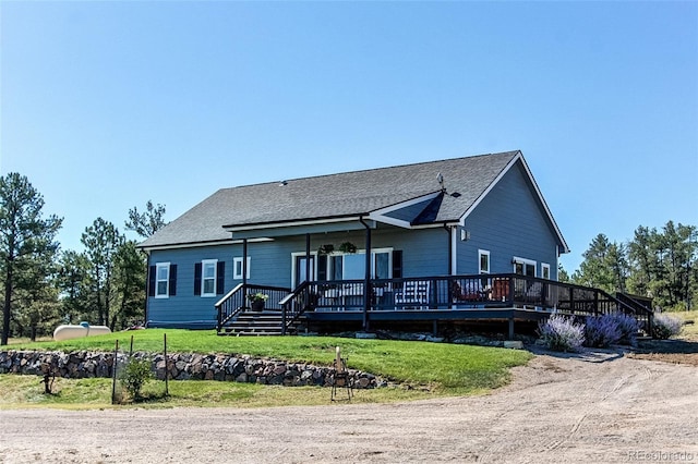 view of front of home with a deck and a front lawn