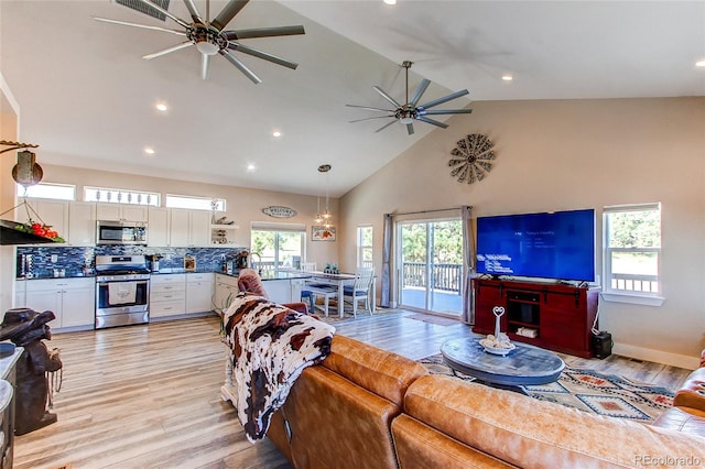 living room featuring light hardwood / wood-style floors, ceiling fan, and high vaulted ceiling