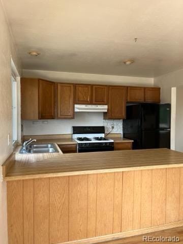 11318 Clermont Dr, Thornton, CO 80233 - kitchen with freestanding refrigerator, white gas range, a sink, under cabinet range hood, and a peninsula