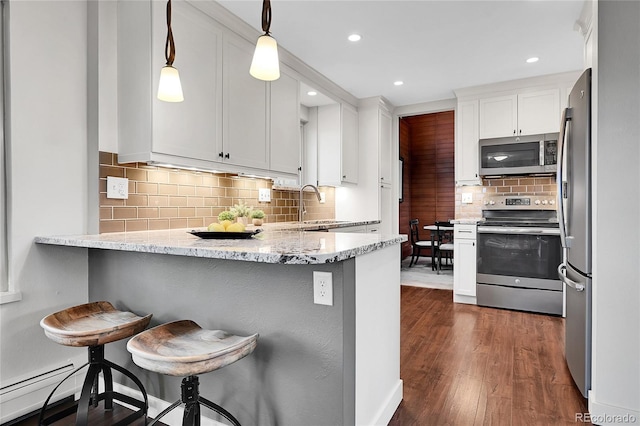 30334 Roan Dr, Evergreen, CO 80439 - kitchen with appliances with stainless steel finishes, a peninsula, baseboard heating, white cabinetry, and backsplash