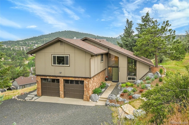 30334 Roan Dr, Evergreen, CO 80439 - view of front of property with board and batten siding, gravel driveway, a garage, stone siding, and a mountain view