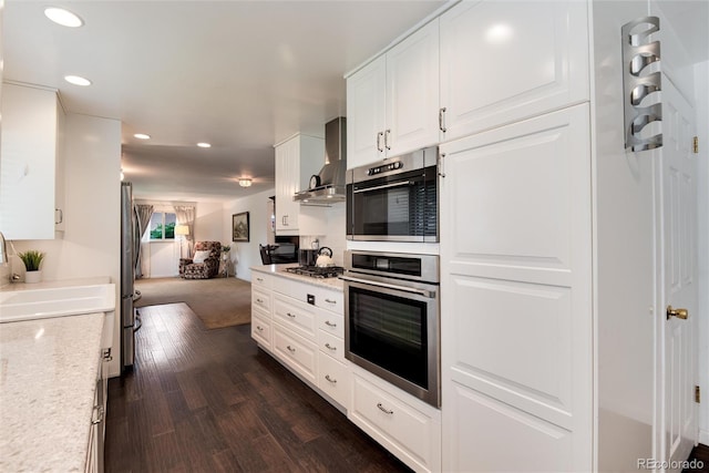 6666 S Pennsylvania St, Centennial, CO 80121 - kitchen with wall chimney range hood, stainless steel gas cooktop, dark wood-style flooring, white cabinetry, and recessed lighting