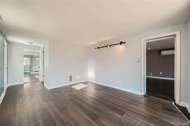 empty room with dark hardwood / wood-style flooring and a wall mounted AC