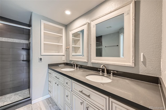 bathroom featuring vanity, a tile shower, hardwood / wood-style flooring, and built in shelves